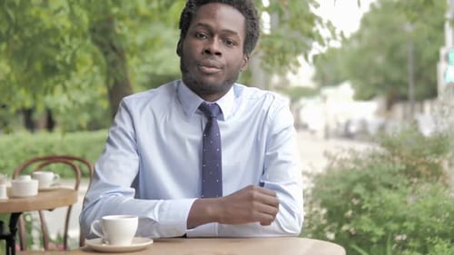 Thumbs Up By African Businessman Sitting in Outdoor Cafe