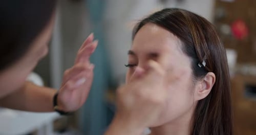 Junge Frau, die sich im Studio von einem Künstler schminkt