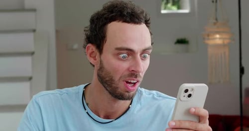 Excited Man Using Smartphone Indoors