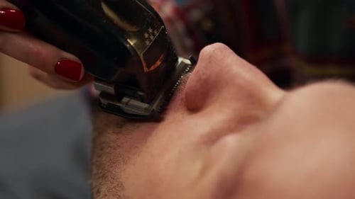 Barbershop: Friseurin schneidet Männerbart mit Rasiermesser