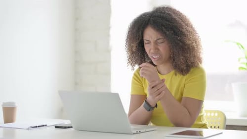 African Woman having Wrist Pain while using Laptop in Office