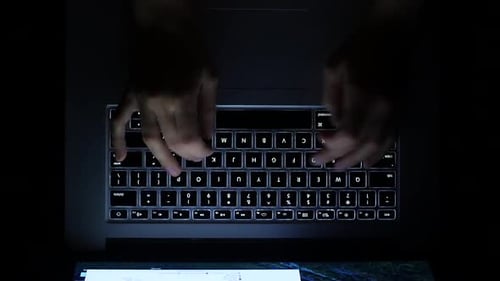Typing on illuminated laptop keyboard in the dark