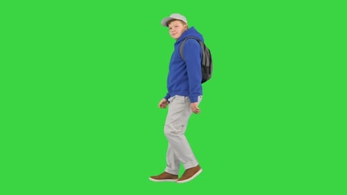 Teenager School Boy Walking By and Making Hello Gesture To Camera on a Green Screen Chroma Key
