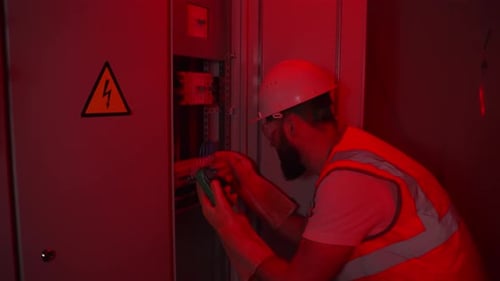 Electrician Working in Red Alarm Light