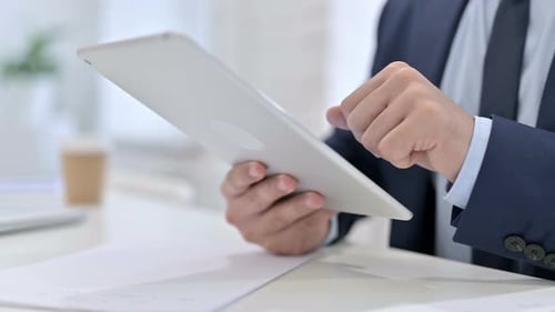 Man Taps Tablet Screen in Office Close Up