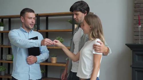 Happy Couple Receiving Apartment Key From Real Estate Agent. Happy Couple Smiling and Getting Keys