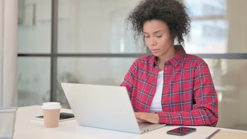 Young Adult Woman Working on Laptop in Modern Office