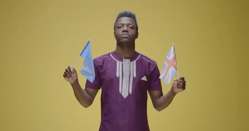 Young Adult Holding Flags Against Yellow Background