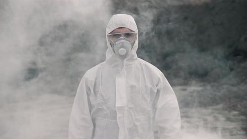 Person in Hazmat Suit Stands Amidst Smoke