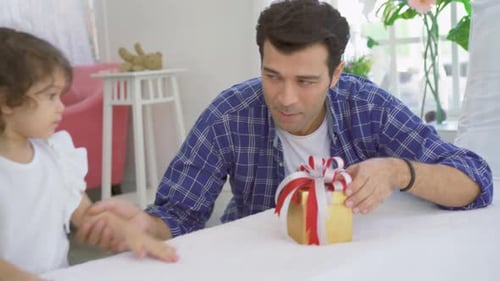 Child Opening a Birthday Gift with an Adult