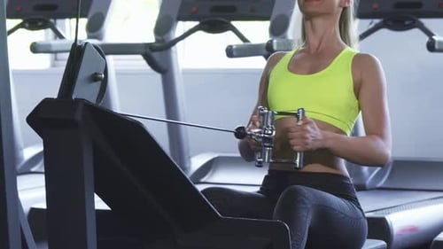 Abgeschnittene Aufnahme einer Sportlerin, die auf einer sitzenden Kabelreihenmaschine trainiert