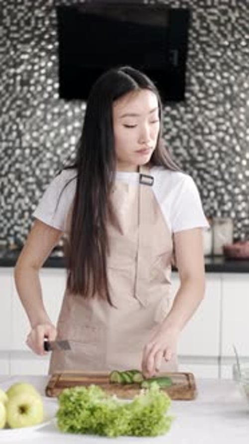 Woman Prepares Salad with Cucumber at Home