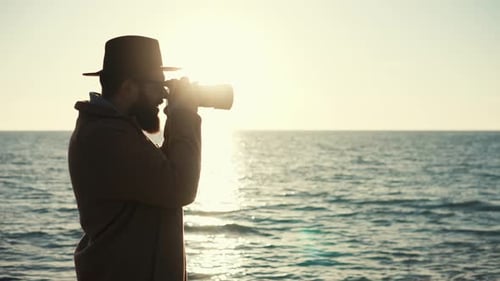 Silhouette eines Fotografen mit Kamera auf dem Hintergrund der Meeresoberfläche