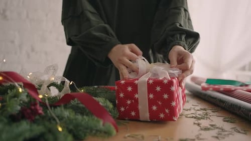 Woman Tying Ribbon on Beautiful Christmas Gift