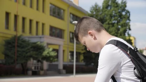A Caucasian Teenage Boy Looks Around and Thinks About Something Closeup a School