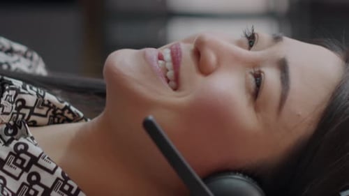 Primer plano de Vídeo vertical del empleado del centro de llamadas con auriculares hablando por teléfono