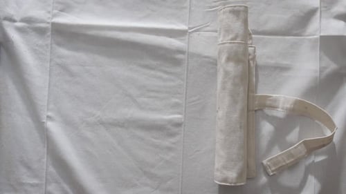 Der Künstler rollt einen Satz Pinsel in einer weißen Stoffhülle von Hand aus. Ansicht von oben
