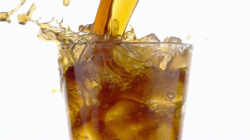 Brown Beverage Poured Over Ice in Glass