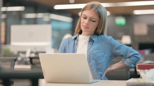 Young Woman Having Back Pain While Using Laptop in Office