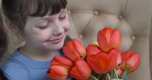 Girl Smelling Red Tulips Bouquet and Smiling