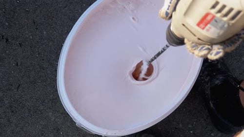 Mezclar pintura blanca en el balde con una batidora de construcción con batidor. Cámara lenta