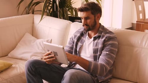 Man Using Tablet, Relaxing on Couch at Home