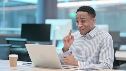 Man Video Conferencing on Laptop in Modern Office