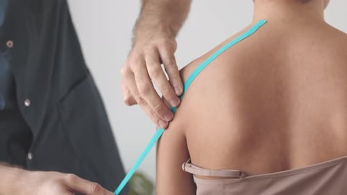 Medical Tape Being Applied to Woman's Shoulder