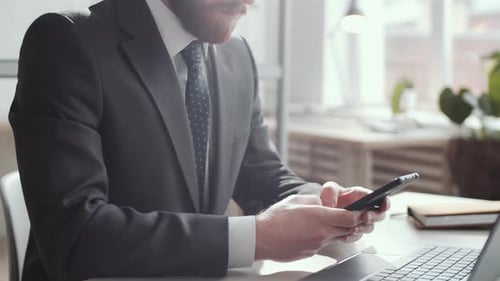 Businessman Texting on Smartphone at Office Desk