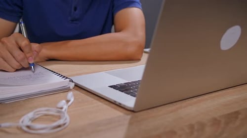 Young Adult Writing in Notebook at Desk