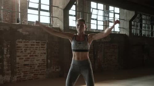 Fit woman doing jumping jack exercise at fitness gym