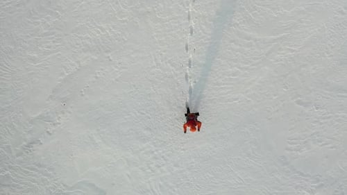Top View a Lone Traveler with a Backpack Walks Through the Snowy Desert