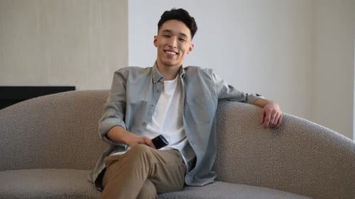 Smiling Young Adult Relaxing on Sofa at Home