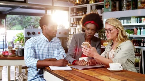 Team Discussing Mobile Technology in Cafe Setting