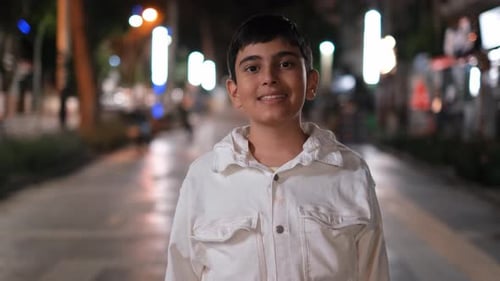 Child Smiling on City Sidewalk at Night