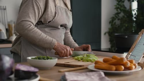 Person Slicing Fresh Vegetables in a Kitchen