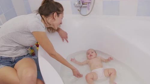 Mother Giving Baby a Bath in Bathtub