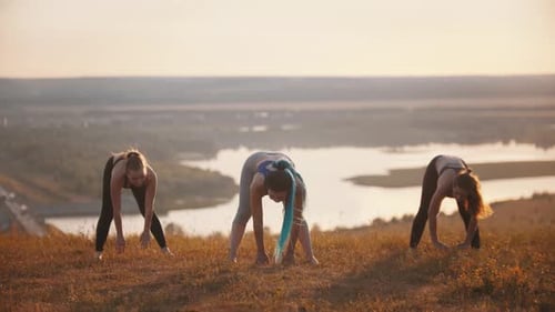 Women Stretching Outdoors at Sunrise on Hilltop