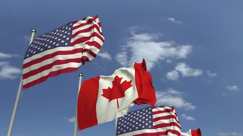Waving Flags of Canada and United States Against Blue Sky