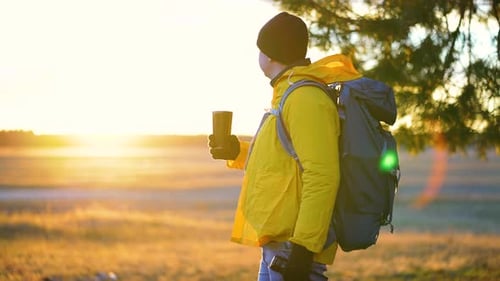 Man with Backpack Drinks Coffee at Sunrise
