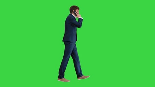 Young Businessman Talking on the Phone While Walking on a Green Screen, Chroma Key.