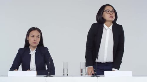 Two Women Speaking at Corporate Event with Microphones
