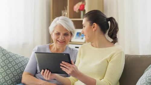 Grandmother and Granddaughter Use Tablet Together on Couch