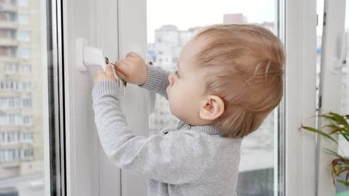 Little baby boy opens window safety lock with key.