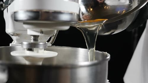Close Up Egg Yolks Pouring into Stand Mixer Bowl