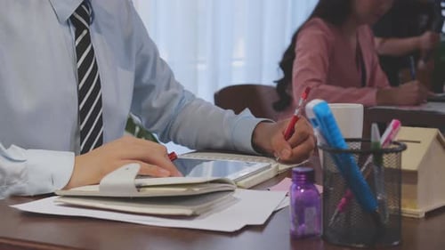 Closeup hands of businessman writing on notebook for report while working at office.