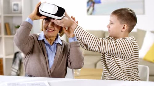 Boy Helping Grandmother Use VR Headset at Home