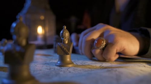 Chess Pieces Moved on Map Under Candlelight