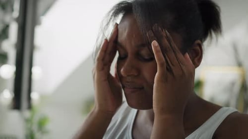 Close up of African-American woman with huge headache standing in the bathroom. Shot with RED helium