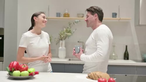 Woman Gives Mug to Man in Bright Kitchen